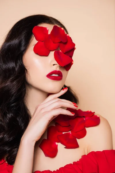 Morena joven con pétalos de rosa roja en la cara aislado en rosa - foto de stock