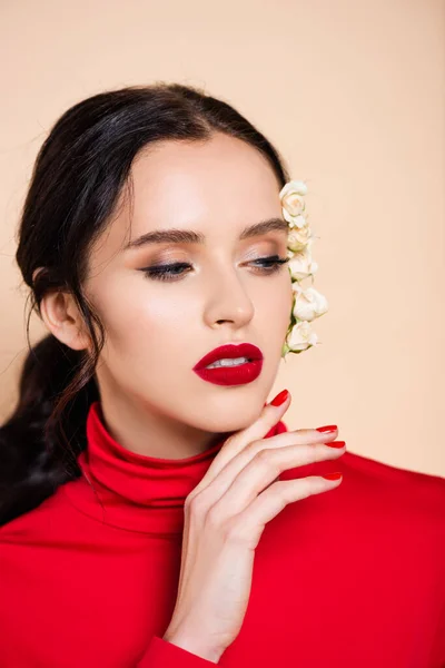 Mujer sensual con labios rojos y flores blancas en la cara mirando hacia otro lado aislado en rosa - foto de stock