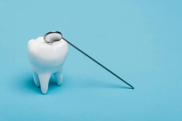 Tooth model and dental mirror on blue background — Stock Photo
