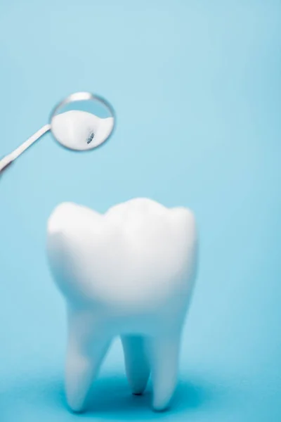 Vista de perto do espelho dentário perto do modelo de dente com rachadura em primeiro plano borrado no fundo azul — Fotografia de Stock