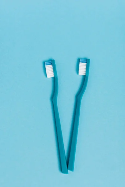 Vista superior de los nuevos cepillos de dientes sobre fondo azul - foto de stock