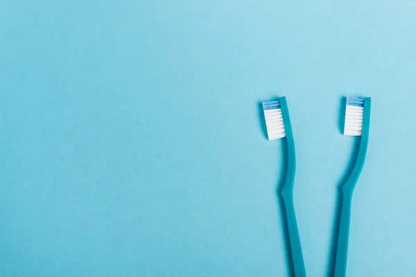 Top view of toothbrushes on blue background with copy space — Stock Photo