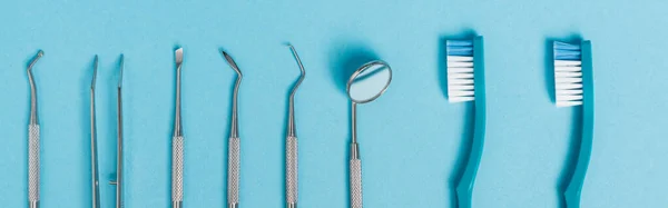 Вид зверху на зубні інструменти та зубні щітки на синьому фоні, банер — стокове фото