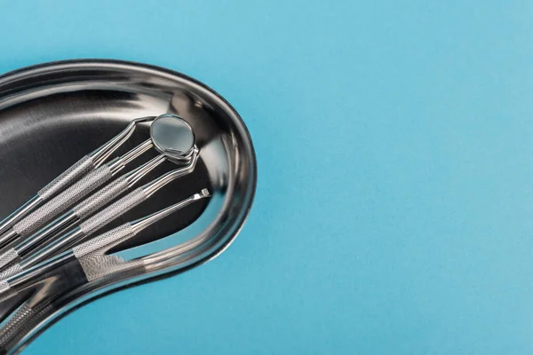 Conjunto de ferramentas dentárias em bandeja de metal sobre fundo azul — Fotografia de Stock