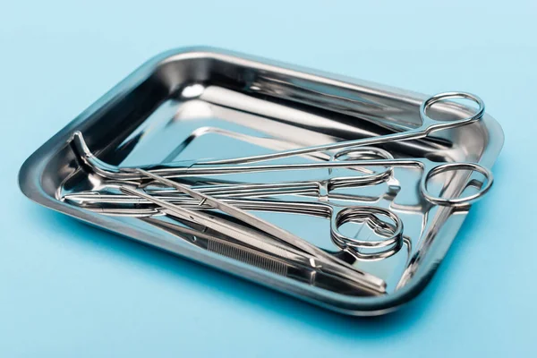 Vista ravvicinata di utensili dentali in acciaio inox in vassoio su sfondo blu — Foto stock