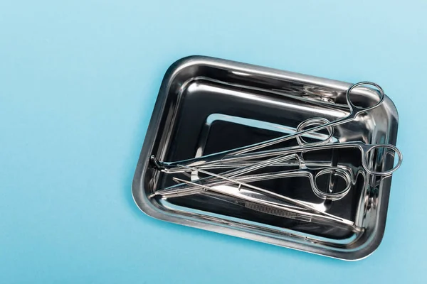 Top view of dental tools and tweezers in tray on blue background — Stock Photo