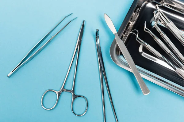 Vista superior de herramientas dentales cerca de bandeja metálica sobre fondo azul - foto de stock