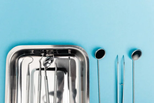Visão superior da linha de ferramentas odontológicas e bandeja no fundo azul — Fotografia de Stock