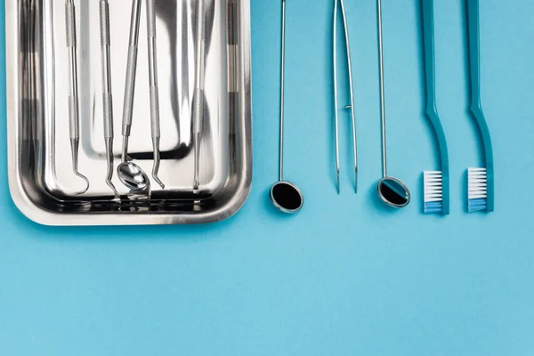 Вид сверху зубных щеток и зубных инструментов на синем фоне — стоковое фото