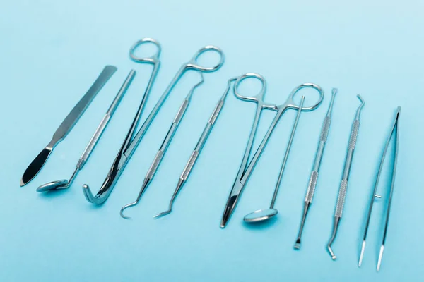 Vista de cerca de la fila de herramientas dentales sobre fondo azul - foto de stock