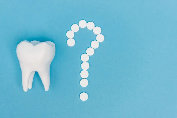 Top view of tooth model and question mark from pills on blue background — Stock Photo