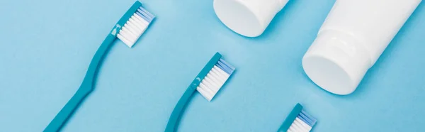 Top view of toothbrushes and toothpaste on blue background, banner — Stock Photo