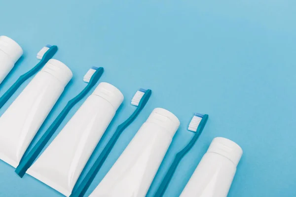 High angle view of toothbrushes and toothpaste on blue background with copy space — Stock Photo