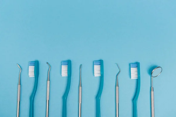 Vista dall'alto di spazzolini da denti e strumenti dentali su sfondo blu con spazio di copia — Foto stock