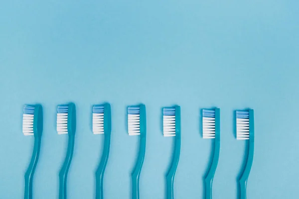 Top view of blue toothbrushes on blue background with copy space — Stock Photo