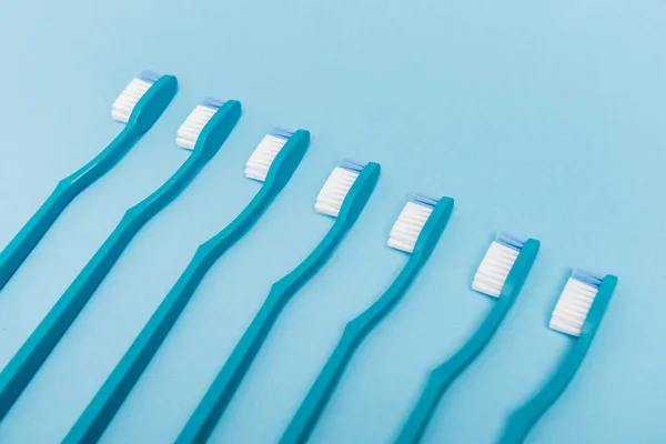 Vista de ángulo alto de cepillos de dientes azules sobre fondo azul - foto de stock