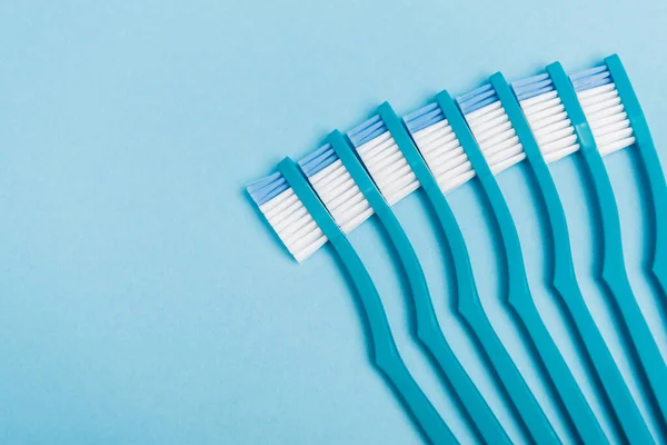 Vista superior de cepillos de dientes limpios sobre fondo azul - foto de stock