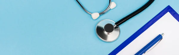 Top view of clipboard and stethoscope on blue background, banner — Stock Photo