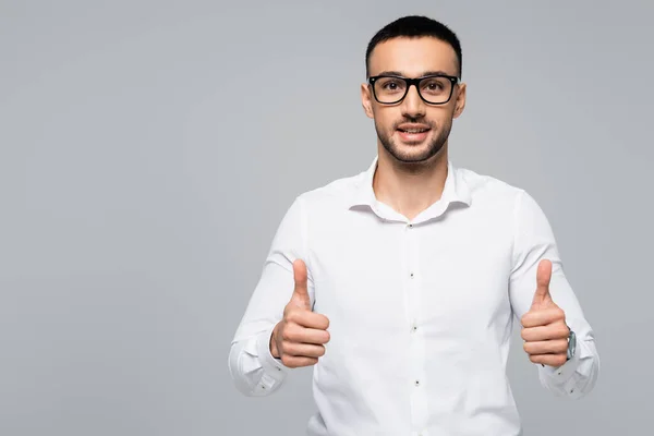 Successful hispanic businessman smiling at camera and showing thumbs up isolated on grey — Stock Photo
