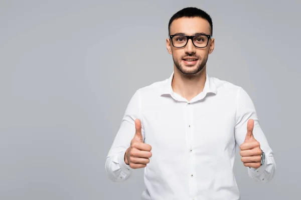 Erfolgreicher hispanischer Geschäftsmann lächelt in die Kamera und zeigt vereinzelt Daumen hoch auf grau — Stockfoto