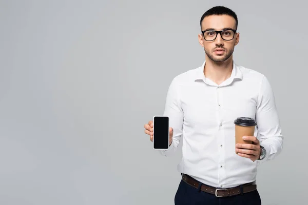 Jovem empresário hispânico segurando café para ir e smartphone com tela em branco isolado em cinza — Fotografia de Stock