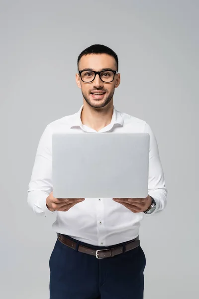 Erfolgreicher hispanischer Geschäftsmann hält Laptop in der Hand und blickt isoliert auf graue Kamera — Stockfoto