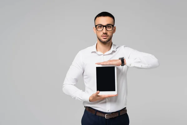 Homme d'affaires hispanique brune dans des lunettes montrant tablette numérique avec écran blanc isolé sur gris — Photo de stock