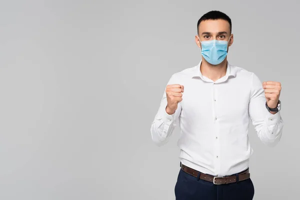 Successful hispanic businessman in medical mask showing win gesture isolated on grey — Stock Photo