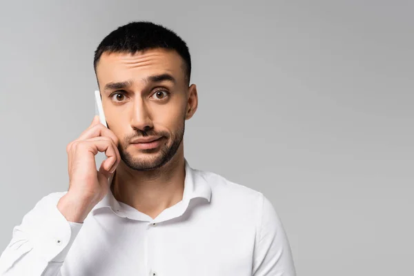 Desanimou empresário hispânico falando no celular isolado no cinza — Fotografia de Stock