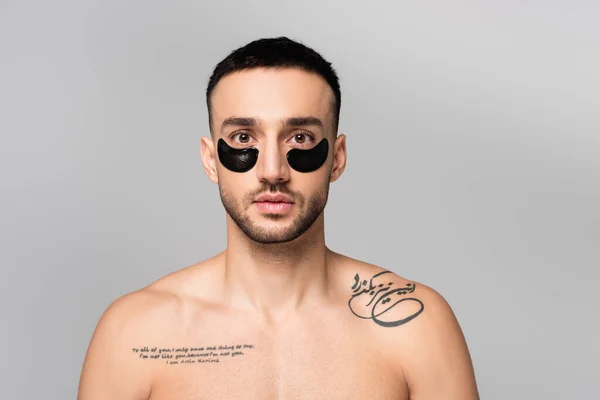 Homme hispanique sans chemise, tatoué avec des patchs pour les yeux regardant la caméra isolée sur gris — Photo de stock