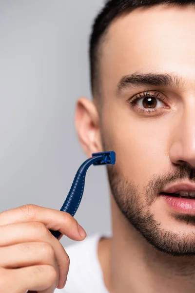 Nahaufnahme junger hispanischer Mann rasiert sich mit Sicherheitsrasierer isoliert auf grau — Stockfoto