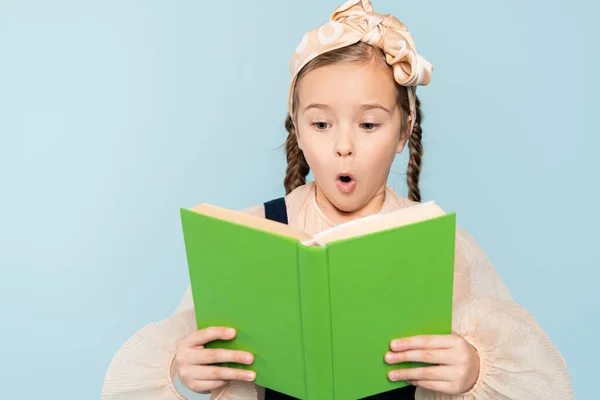 Choqué petite fille avec des nattes lecture livre isolé sur bleu — Photo de stock