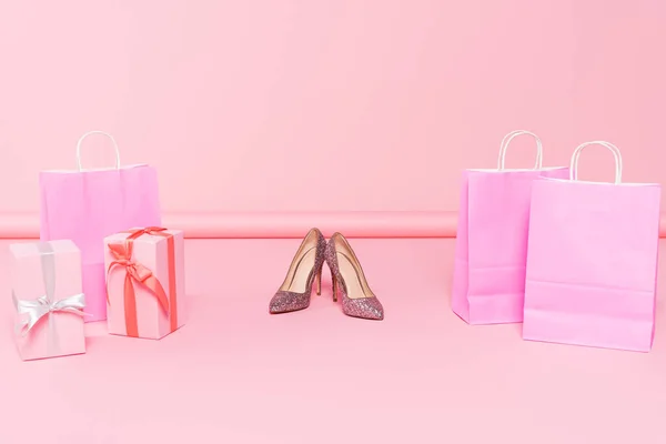 Tacones cerca de bolsas de compras y cajas de regalo en rosa - foto de stock