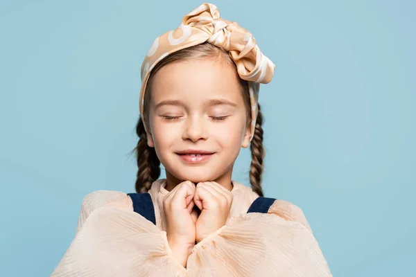 Criança alegre na cabeça com arco com olhos fechados isolados em azul — Fotografia de Stock
