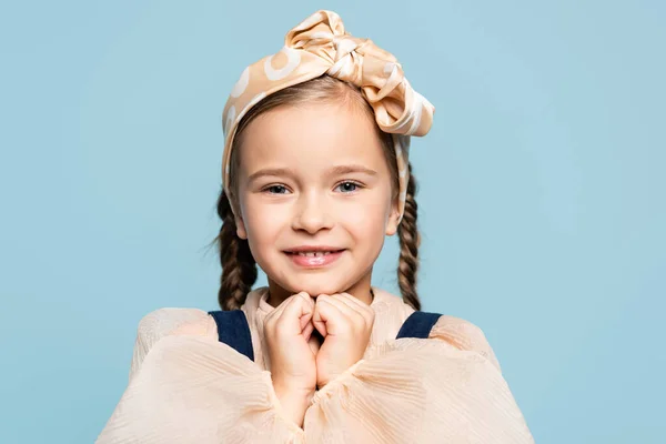 Bambino positivo in fascia con arco guardando la fotocamera isolata su blu — Foto stock