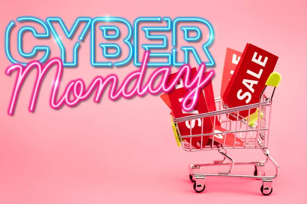 Red labels with sale in small shopping trolley near cyber monday lettering on pink — Stock Photo