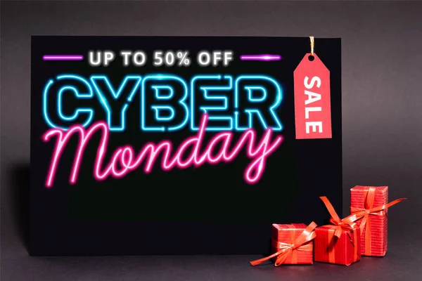 Plakat mit bis zu 50 Prozent Rabatt, Cyber-Monday-Schriftzug und Verkaufsetikett in der Nähe von Geschenken auf dunklem Hintergrund — Stockfoto