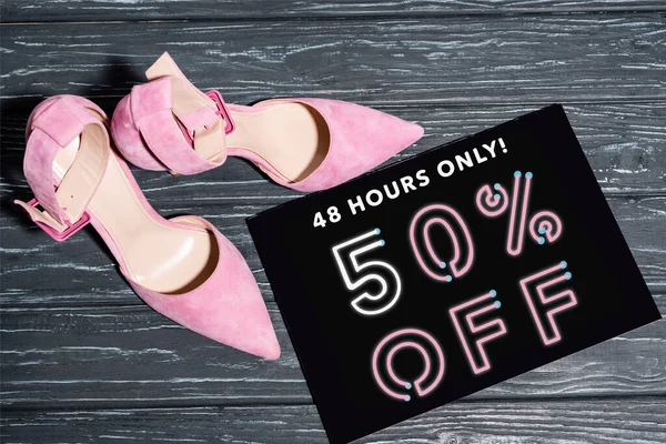 Vista superior de los zapatos de color rosa cerca de la pancarta con solo 48 horas, 50 por ciento de descuento en letras en la superficie de madera - foto de stock