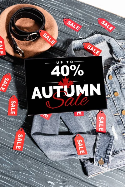 Blaue Jeansjacke mit Baskenmütze, Gürtel und Plakat mit bis zu 40 Prozent Rabatt, Herbstschlussverkauf-Schriftzug auf Holzoberfläche — Stockfoto