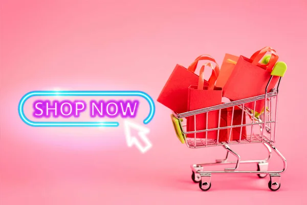 Borse shopping in piccolo carrello vicino al negozio ora lettering su rosa, concetto venerdì nero — Foto stock