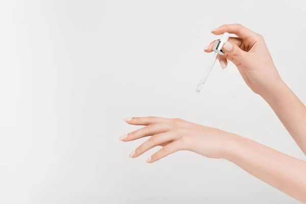 Vista recortada de la mujer sosteniendo la pipeta con suero aislado en blanco - foto de stock