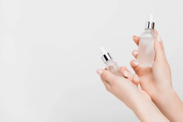 Vista ritagliata di donna che tiene bottiglie con siero in mani isolate su bianco — Foto stock