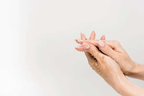Vista recortada de la mujer aplicando exfoliante en las manos aisladas en blanco - foto de stock