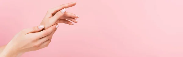 Visão parcial da mulher aplicando creme cosmético em mãos isoladas em rosa, banner — Fotografia de Stock