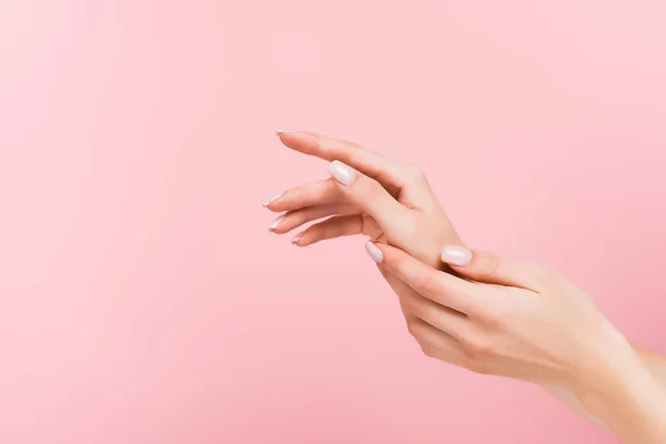 Partial view of woman applying cosmetic cream on hands isolated on pink — Stock Photo