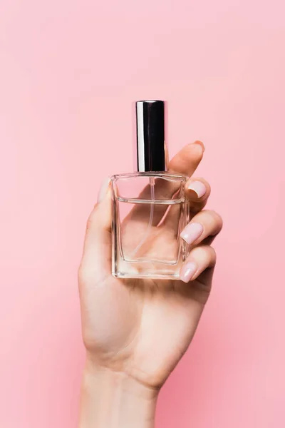 Vista cortada da mulher segurando garrafa com perfume de luxo na mão isolado em rosa — Fotografia de Stock