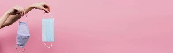 Vista parziale della donna che tiene maschere mediche e di cotone isolate su rosa, banner — Foto stock