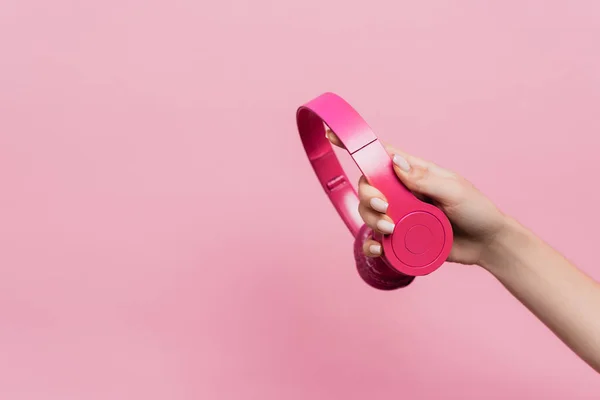 Vue recadrée de la femme tenant des écouteurs sans fil isolés sur rose — Photo de stock