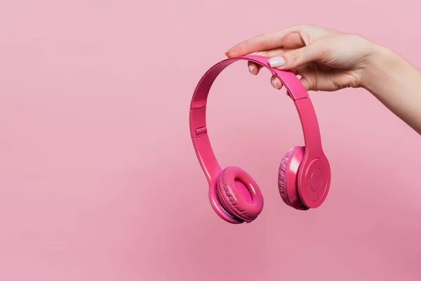 Partial view of woman holding wireless headphones isolated on pink — Stock Photo