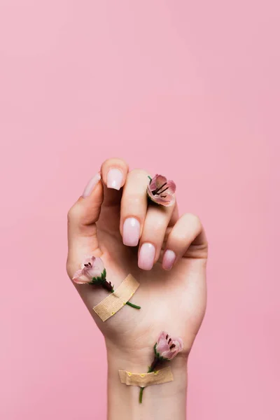 Bandagen mit Blumen an weiblicher Hand isoliert auf rosa — Stockfoto